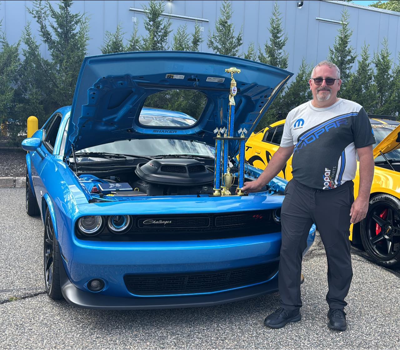 Jim standing with his B5 Blue Challenger and trophies at the Clifton car show